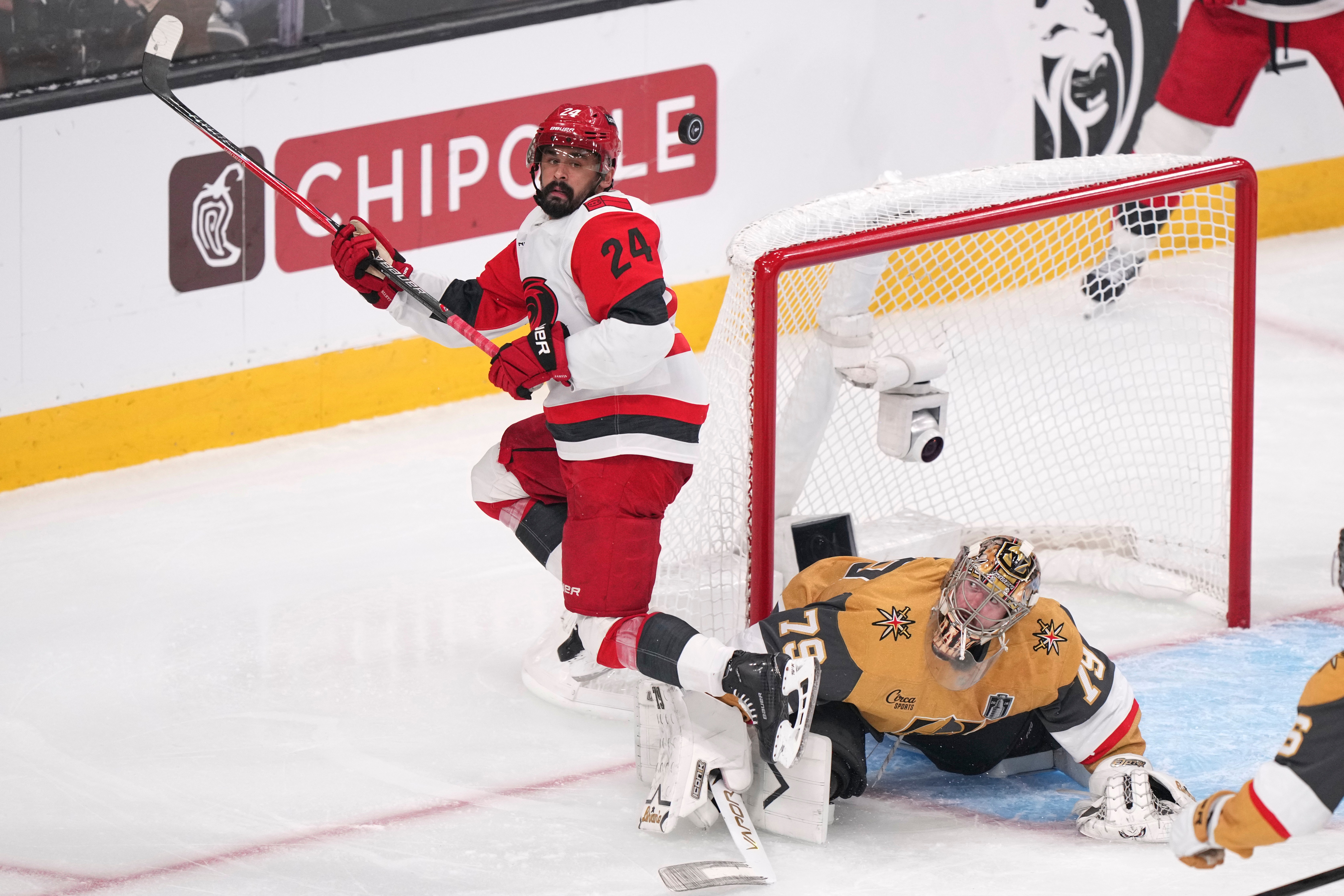 FILE - Carolina Hurricanes right wing Seth Jarvis, left, tries to know a the puck out of the air as Vegas Golden Knights goaltender Carter Hart defends during the third period in Game 4 of the NHL hockey Stanley Cup Final series June 9, 2026, in Las Vegas. 