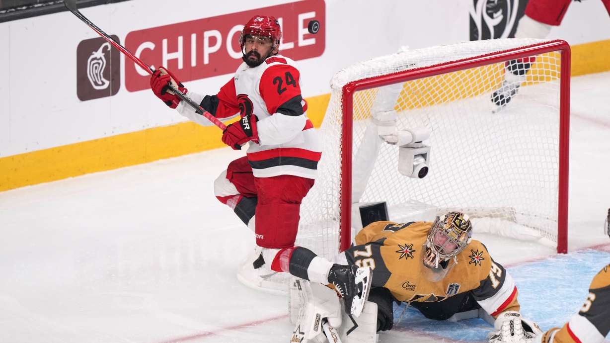 FILE - Carolina Hurricanes right wing Seth Jarvis, left, tries to know a the puck out of the air as Vegas Golden Knights goaltender Carter Hart defends during the third period in Game 4 of the NHL hockey Stanley Cup Final series June 9, 2026, in Las Vegas.