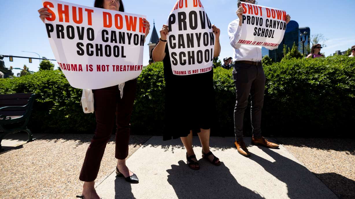 People hold signs during a press conference about recent allegations of abuse at the Provo Canyon School outside of the Provo Historic Courthouse in Provo on June 15. Provo Canyon School's Provo campus license was revoked Friday by the state of Utah following continued allegations of abuse.
