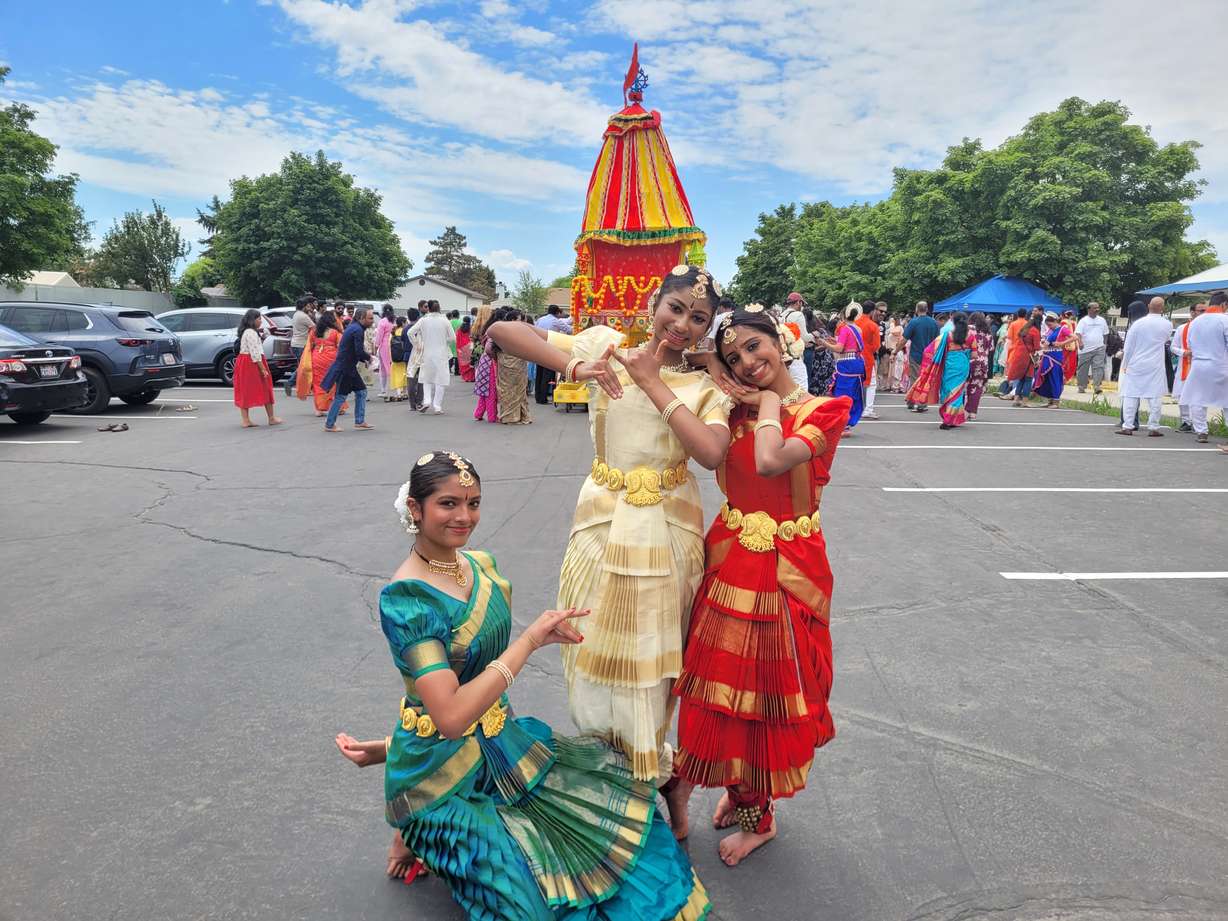 From left to right, Saloni Shah, Iyra Maringanti and Poorvi Nandiraju pose behind the Ratha containing Hindu gods in Kearns on Saturday, July 18, 2026.