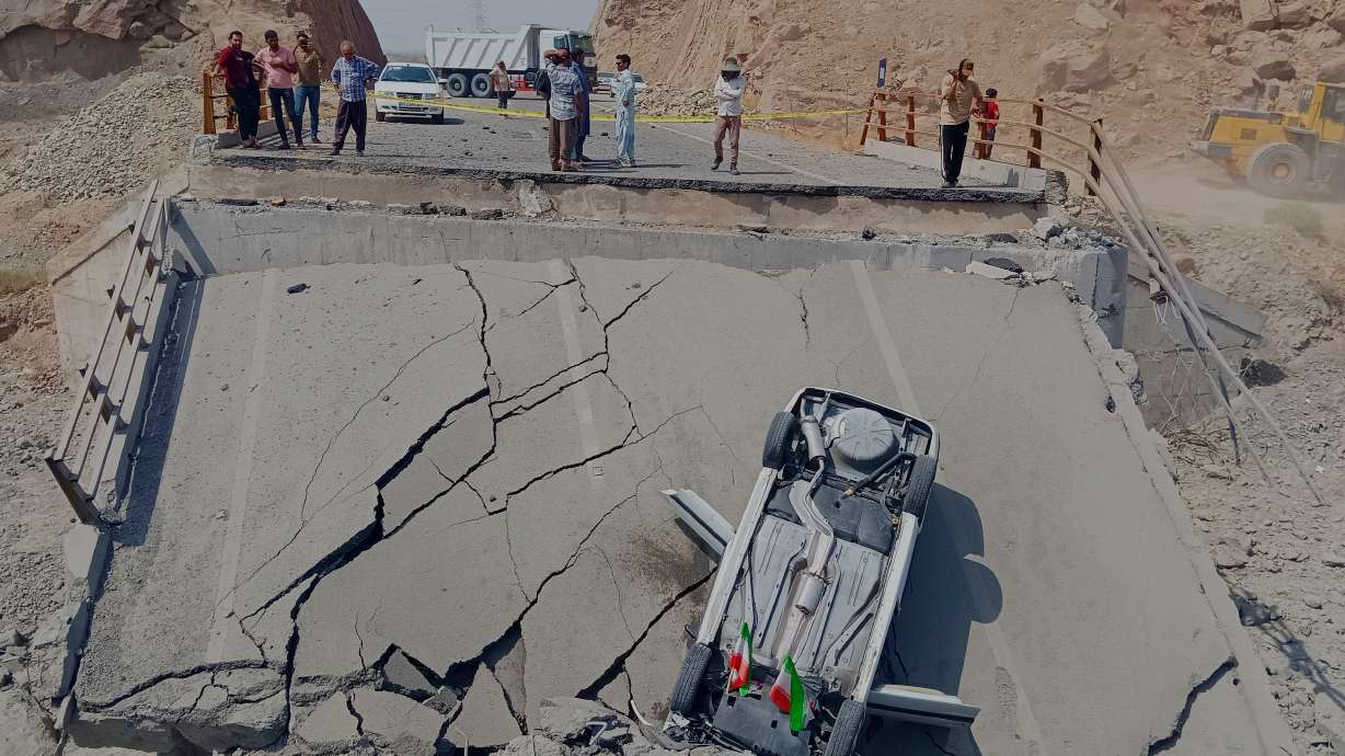 An overturned car sits on a section of a destroyed bridge after a strike in Hormozgan province, southern Iran, Saturday.