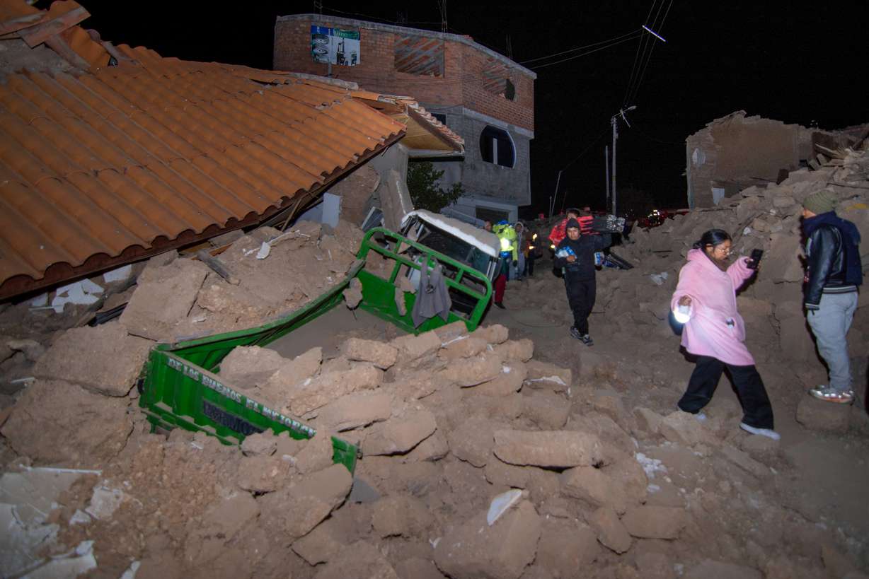 Residents walk amid the debris of homes that collapsed after an earthquake struck Pumpuya, Peru, Sunday.