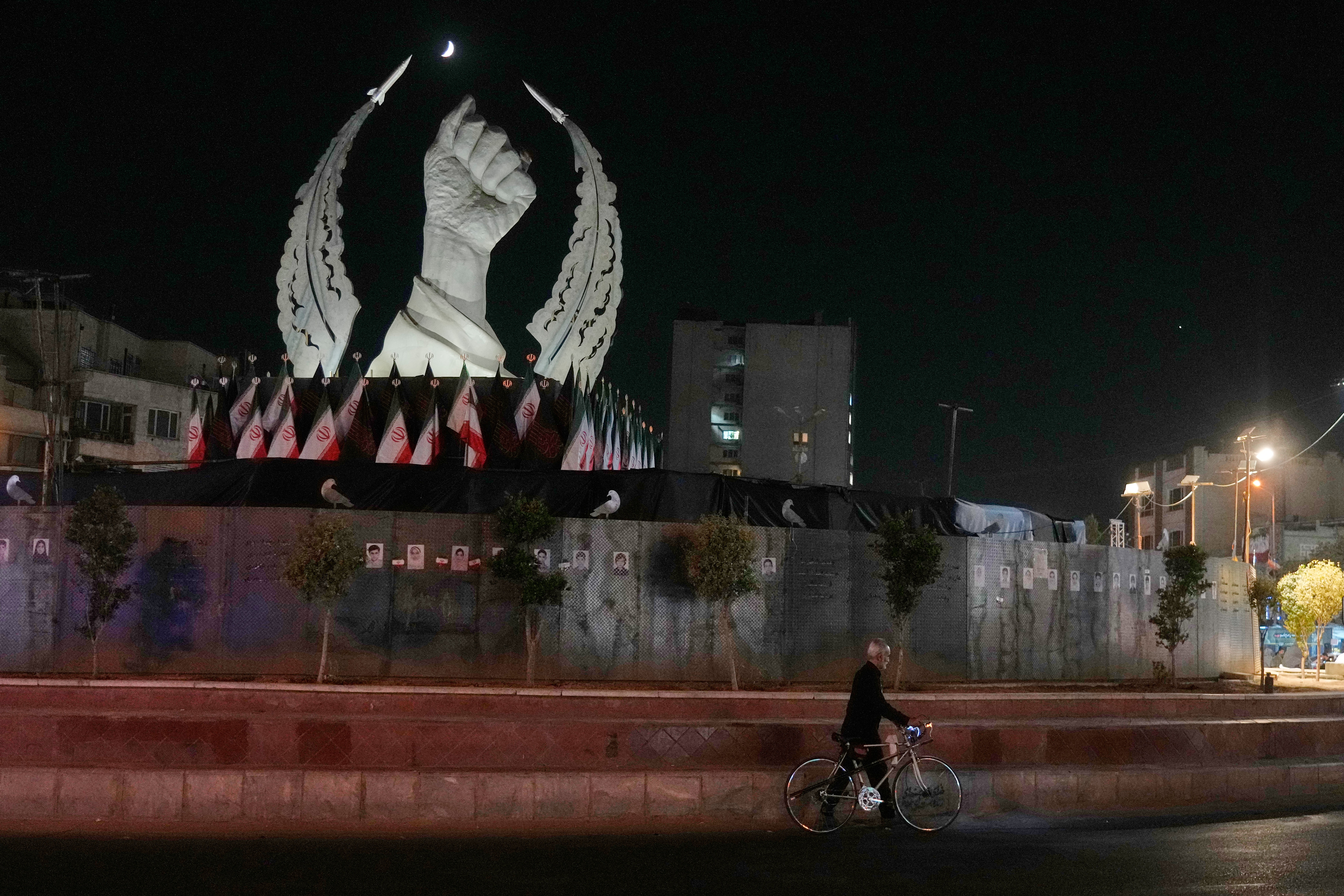 A man carries his bicycle in front of a monument depicting the clenched fist of the late Iranian Supreme Leader Ayatollah Ali Khamenei, who was killed in the U.S. and Israel strike on Feb. 28, in Islamic Revolution Square in Tehran, Sunday.