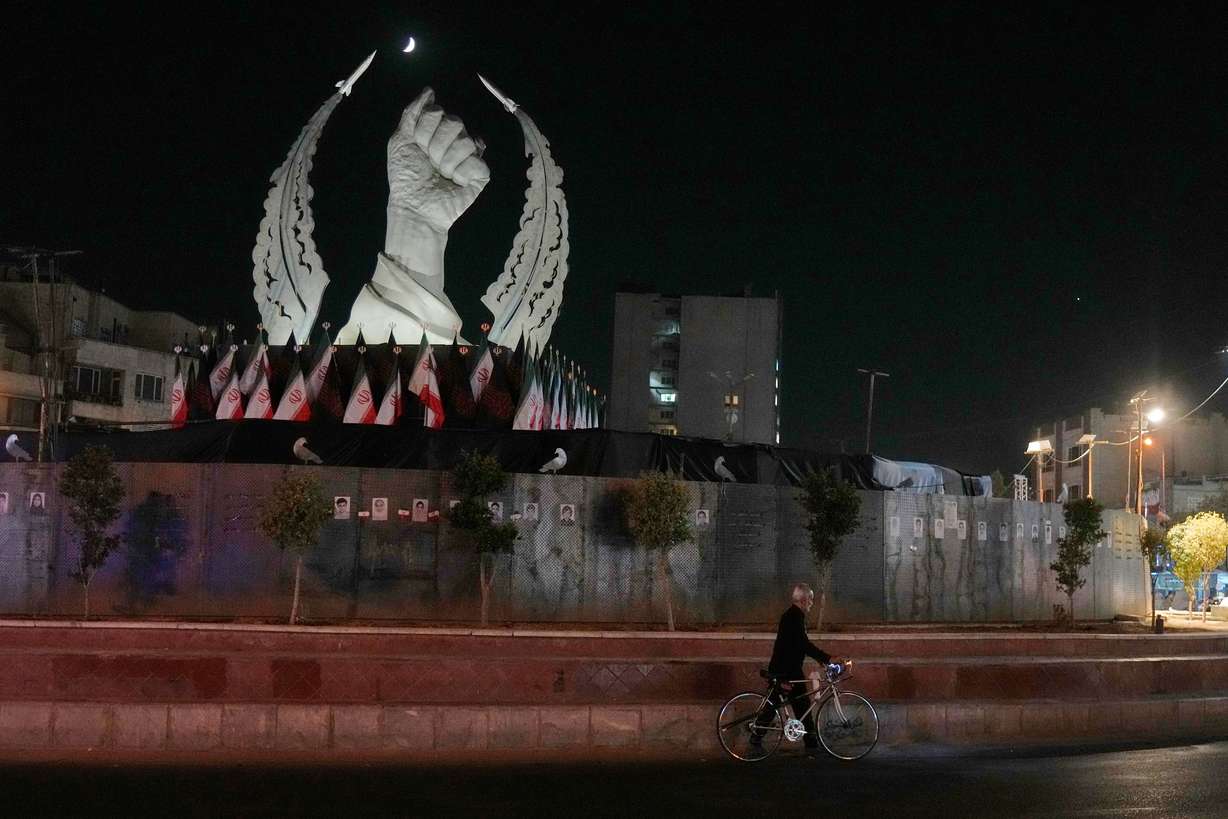 A man carries his bicycle in front of a monument depicting the clenched fist of the late Iranian Supreme Leader Ayatollah Ali Khamenei, who was killed in the U.S. and Israel strike on Feb. 28, in Islamic Revolution Square in Tehran, Sunday.