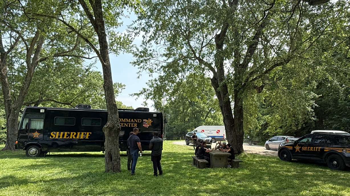 Officials stand at a staging area after an operation to recover multiple people who died while trying to save someone from the Scioto River in the Columbus suburb of Powell, Ohio, Monday. Five people died in the incident, the Delaware County sheriff said.