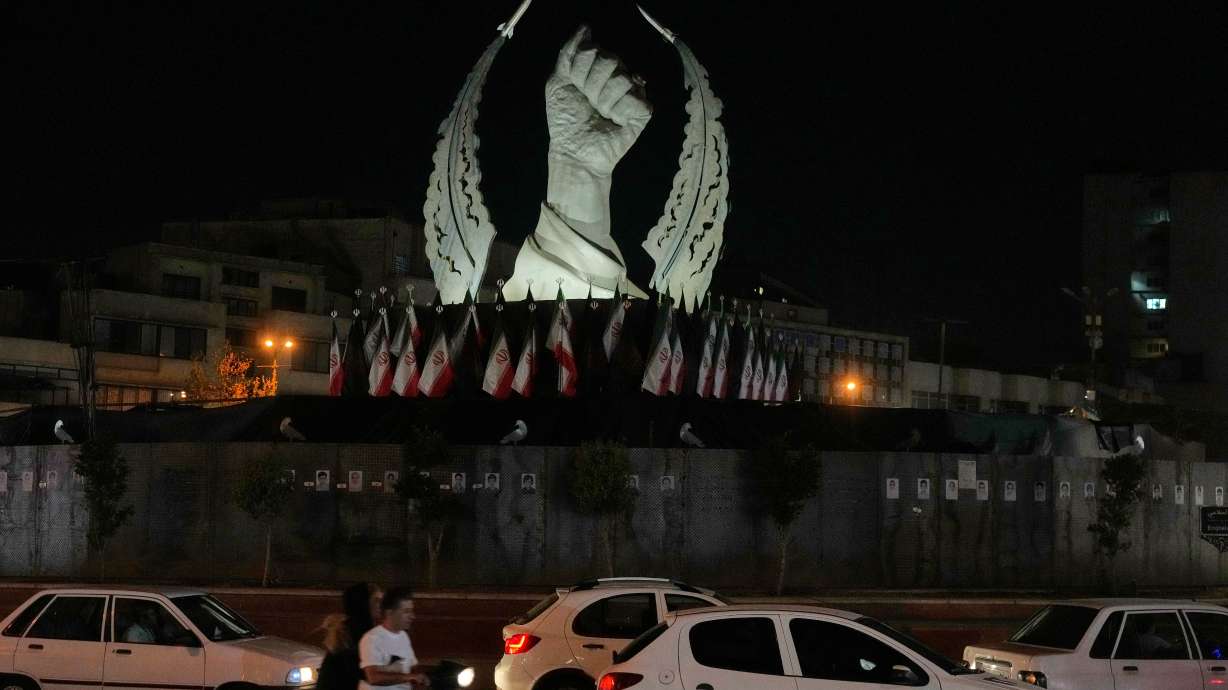 Vehicles drive past a monument depicting the clenched fist of the late Iranian Supreme Leader Ayatollah Ali Khamenei, who was killed on Feb. 28, in Islamic Revolution Square in Tehran, Sunday. The U.S. and Iran continued to exchange fire on Wednesday, raising concerns about diplomacy.