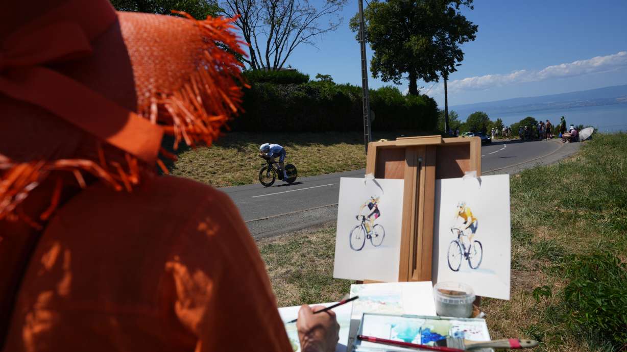 A woman draws as Britain's Fred Wright rides during the sixteenth stage of the Tour de France cycling race, an indivdual time-trial with start in Evian-Les-Bains and finish in Thonon-les-Bains, France, Tuesday, July 21, 2026.