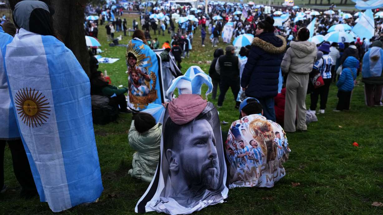 An Argentina fan wrapped in a flag bearing an image of Lionel Messi gathers outside the Argentine Football Association headquarters while waiting for the national team to arrive in Ezeiza, on the outskirts of Buenos Aires, Monday, July 20, 2026, following its World Cup final loss to Spain.