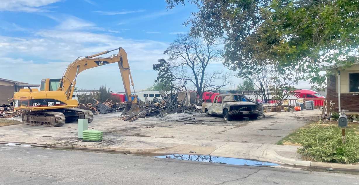 A FrontRunner train on Tuesday passes behind the charred remains of a Roy home destroyed in a fire a day earlier. One fire official suspects sparks from a passing train may be the culprit though authorities are still investigating.