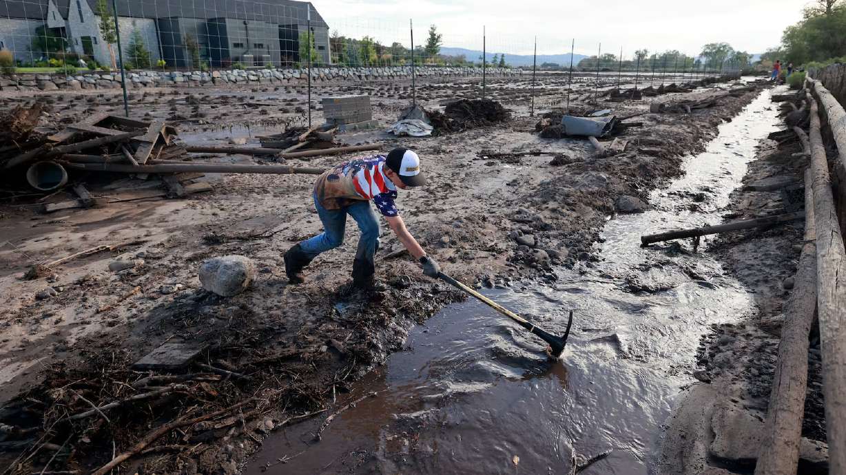 Rhett Beacham, 9, helps clear debris so flood waters can flow freely after flooding in Beaver on Monday. Behind him is a flooded lavender farm.