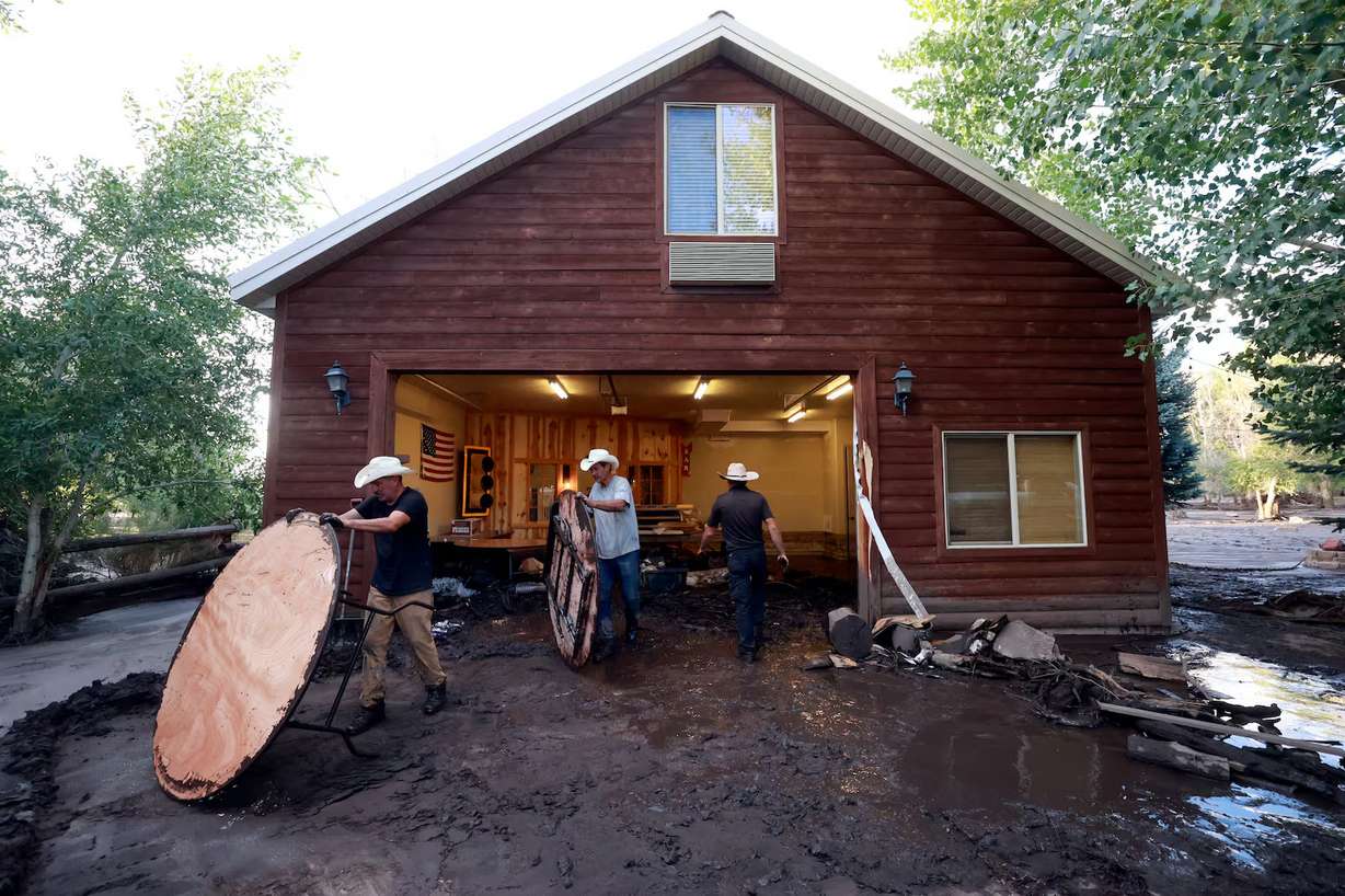 Aaron Richardson, Curtis Street and Trendon Delray clean out Richardson’s flooded garage after flooding in Beaver on Monday. Richardson stored furniture for the Beaver River Ranch Wedding and Event Center in the garage, including the tables covered in mud. He still plans to host a wedding in early August.