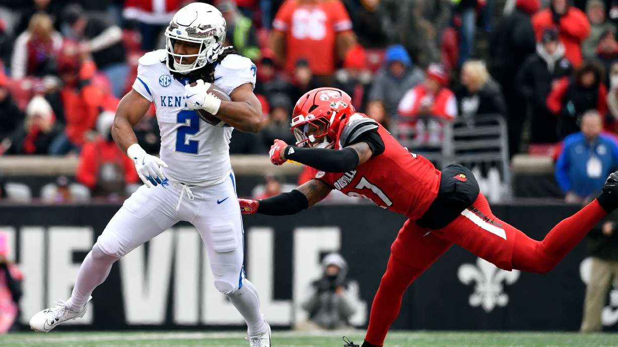 FILE - Kentucky running back Dante Dowdell (2) avoids the tackle attempt by Louisville defensive back Jojo Evans Jr. (27) during the second half of an NCAA college football game in Louisville, Ky., Nov. 29, 2025.