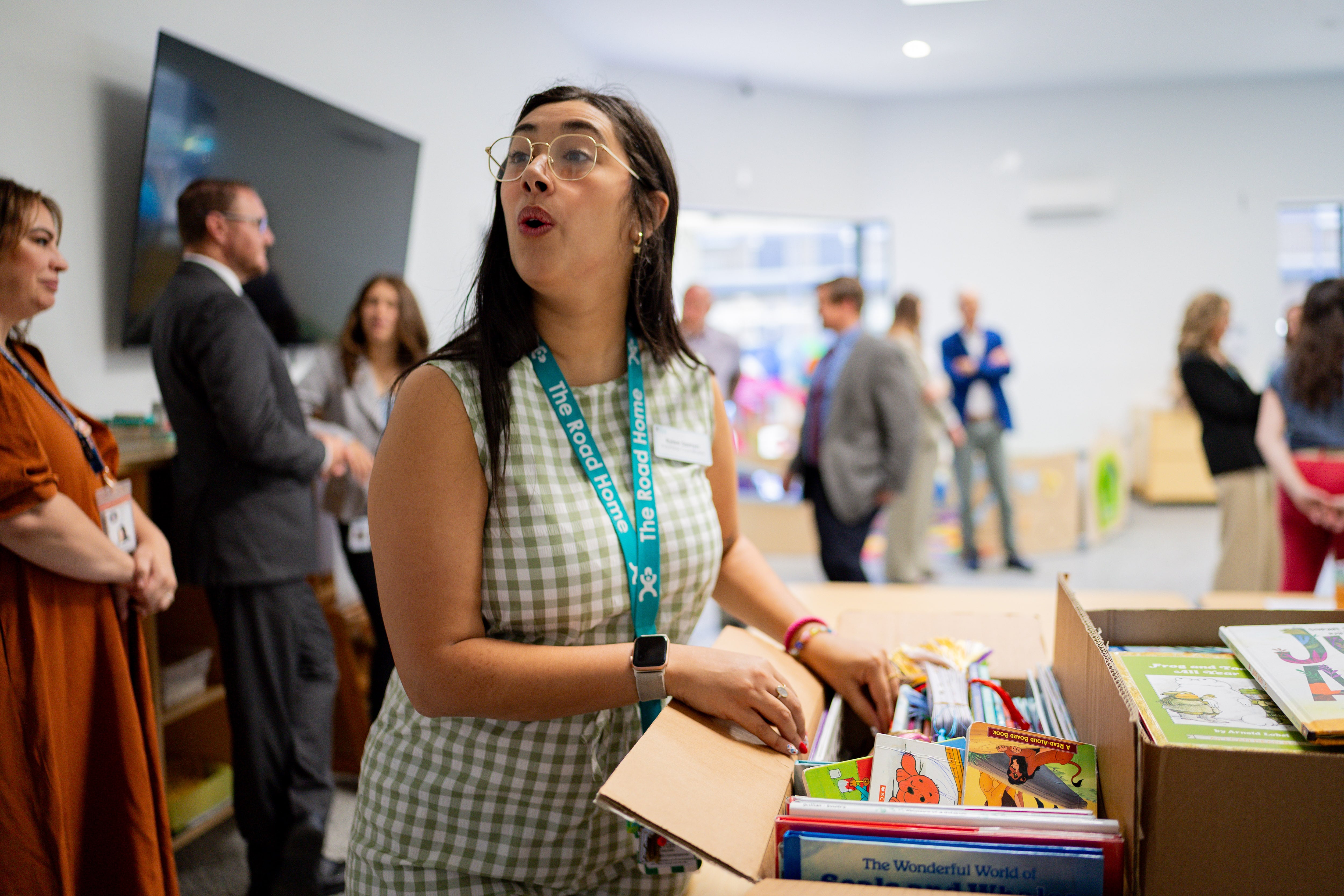 Rylee Samyn, volunteer coordinator with The Road Home, center, looks through books after first lady Abby Cox read to children and promoted early literacy at The FINCH (Family Interim Noncongregate Housing), operated by The Road Home, in South Salt Lake on Tuesday.