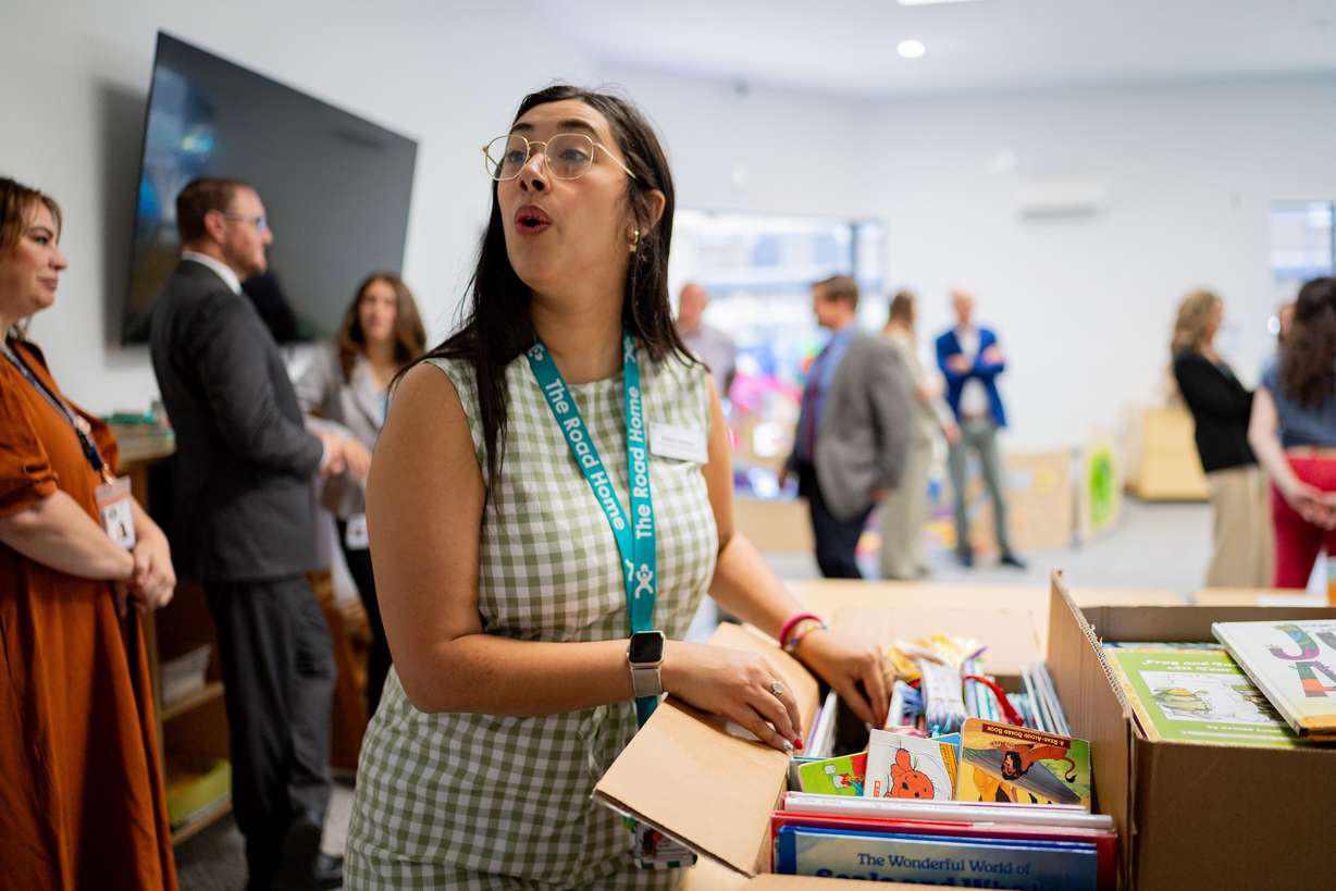 Rylee Samyn, volunteer coordinator with The Road Home, center, looks through books after first lady Abby Cox read to children and promoted early literacy at The FINCH (Family Interim Noncongregate Housing), operated by The Road Home, in South Salt Lake on Tuesday.