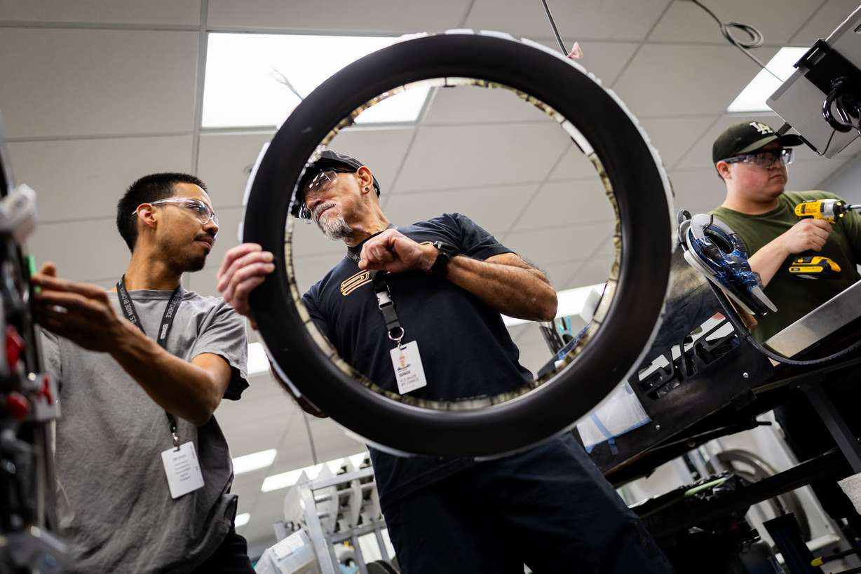 Lay up technician Gonzalo Ramos, left, learns from Oscar Gorritti, supervisor of lay up area, center, while he is working on putting the rim together at the ENVE Composites factory in Ogden on July 17.