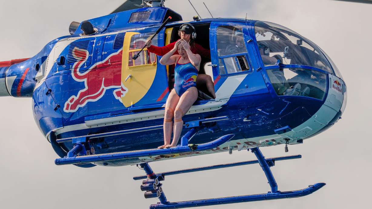 This image released by Discovery Channel shows high diver Molly Carlson preparing to leap 50 feet from a helicopter into a cage surrounded by reef sharks in an episode for Discovery's annual "Shark Week."