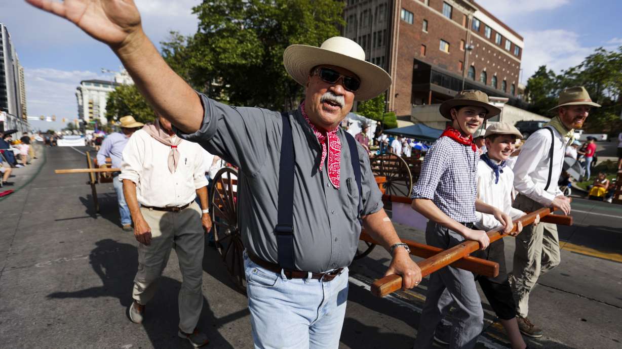 A parade participant waves while walking with The National Society of The Sons of Utah Pioneers during the Days of ’47 Parade in Salt Lake City on July 24, 2025. The event will celebrate Utah's pioneer settlement and America 250 this year.