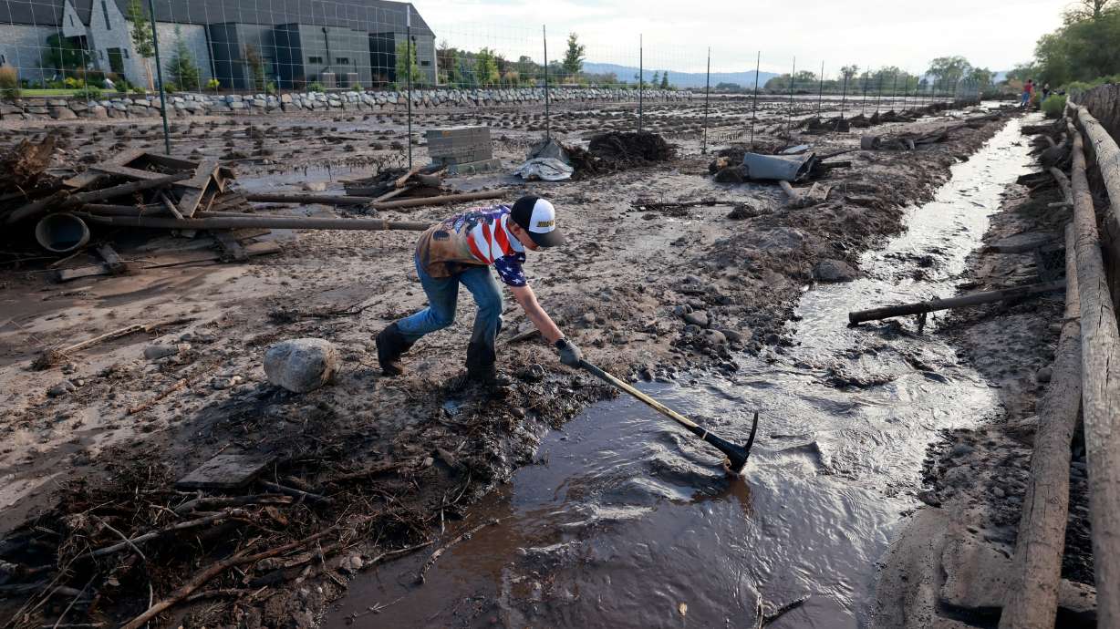 Rhett Beacham, 9, helps clear debris so floodwaters can flow freely after flooding in Beaver on July 20. Utah is offering new loan relief options for farmers and ranchers with state loans.