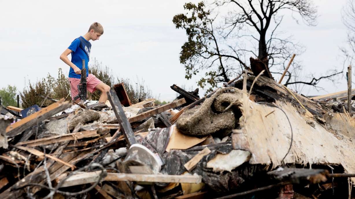 Ty Visage, 16, recovers his airsoft gun from the remnants of his home in Roy on Wednesday. A fire on Monday along a railroad corridor paralleling 2675 West destroyed three homes and around 30 outbuildings.