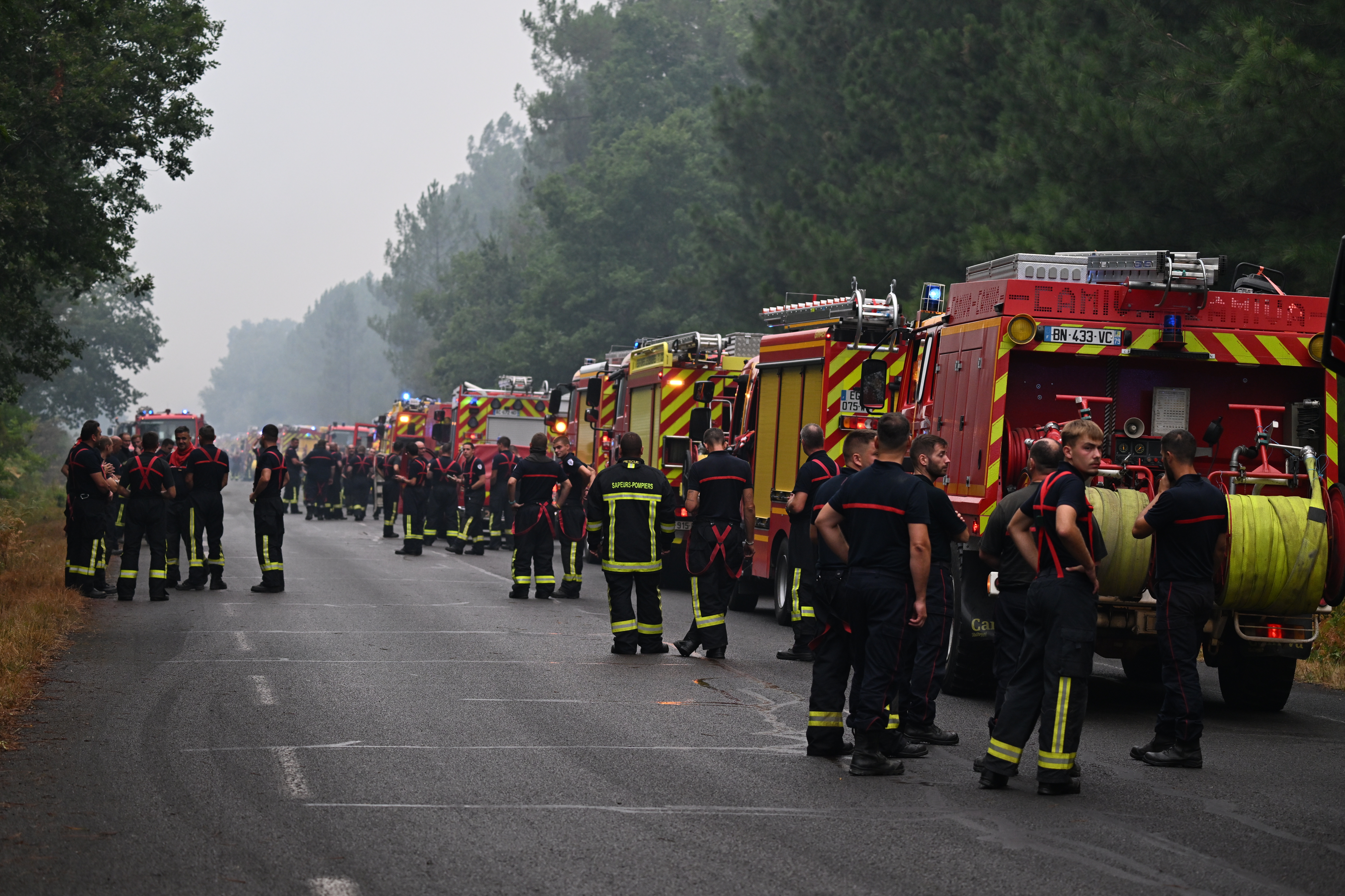 Firefighters wait on a road near Lacanau, southwestern France, on Saturday.