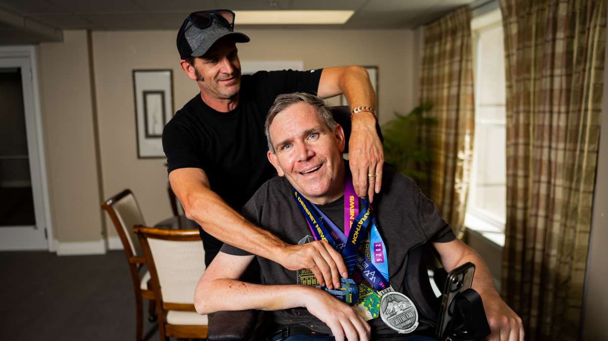 Danny Connolly puts a medal around his brother Brian Connolly’s neck received when he pushed Brian, who has MS, in a wheelchair, in the 2024 Deseret News Marathon at Brian's condominium in Salt Lake City on Tuesday. The Connollys also ran Friday's marathon.