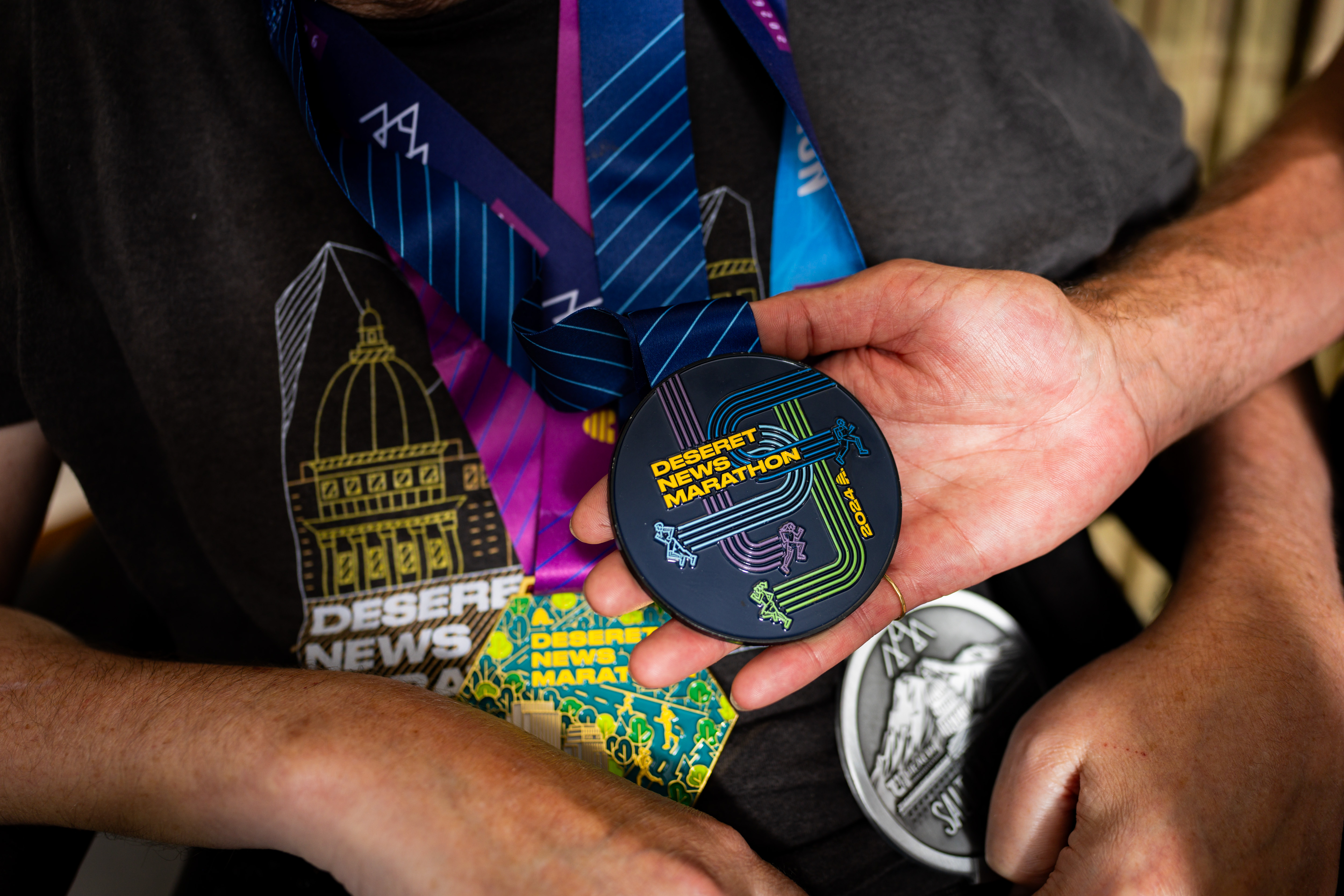 Danny Connolly holds onto a medal he received while pushing his brother Brian Connolly, who has MS, in a wheelchair in the 2024 Deseret News Marathon in a common area at Brian's condominium in Salt Lake City on Tuesday. The Connollys also ran in Friday's marathon.