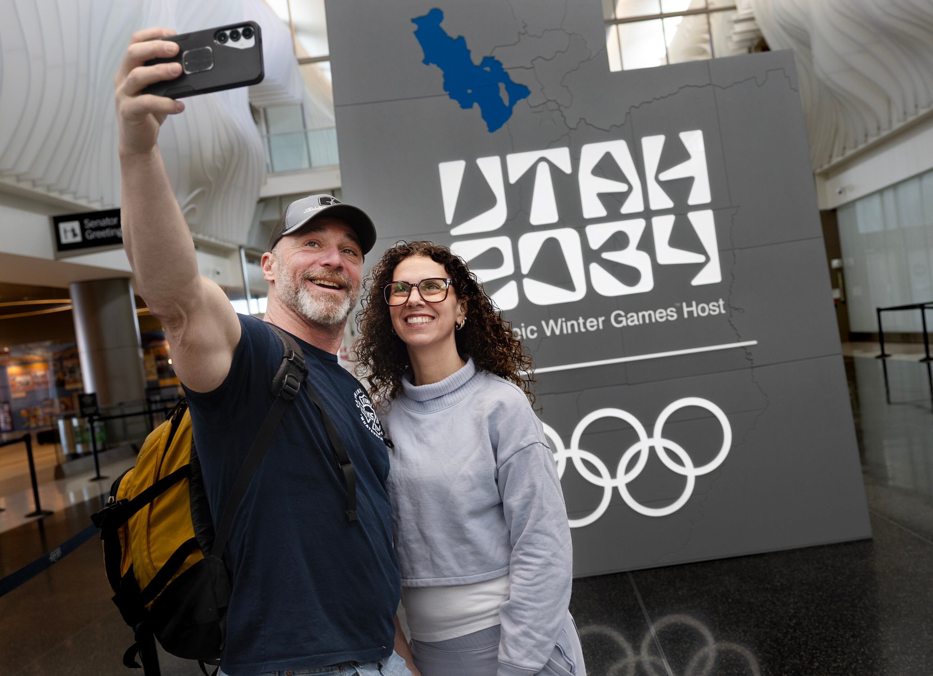 Craig and Annemarie Mosia of Long Island, N.Y., take a photo in front of the “Utah 2034” Olympics logo at the Salt Lake City International Airport on Feb. 20. Steve Starks said the name change was meant to unify Utahns.