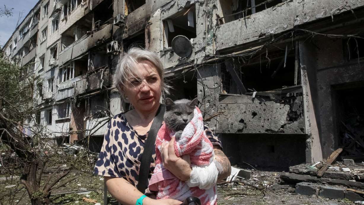 A woman with her cat stands near an apartment building hit by a Russian airstrike in the town of Pavlohrad in eastern Ukraine on July 20.