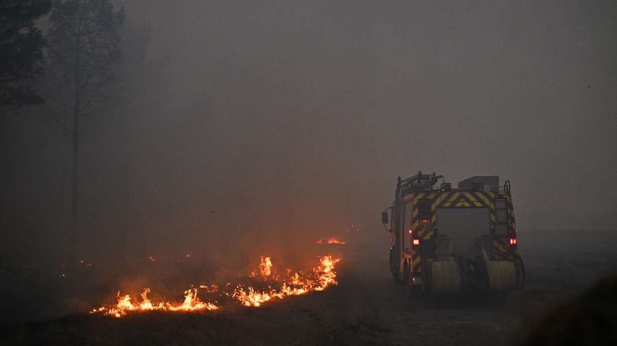 A fire engine drives through smoke of a wildfire raging near Marcheprime, outside, Bordeaux, France, Sunday.