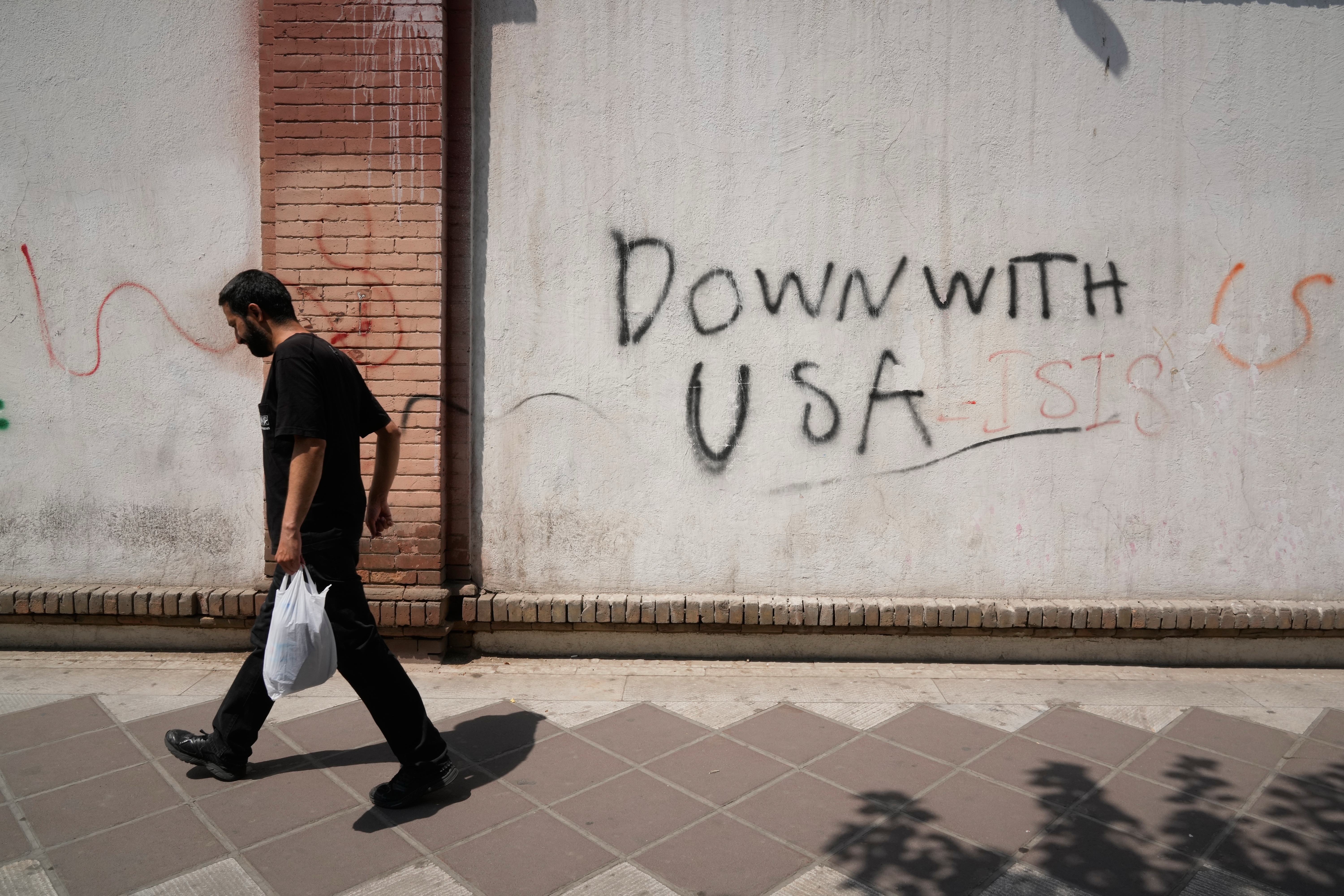 A man walks past anti-U.S. graffiti on the wall of the British Embassy in Tehran, Iran, Monday. President Donald Trump and Israeli Prime Minister Benjamin Netanyahu are meeting on Tuesday in their first talks since launching the Iran war.