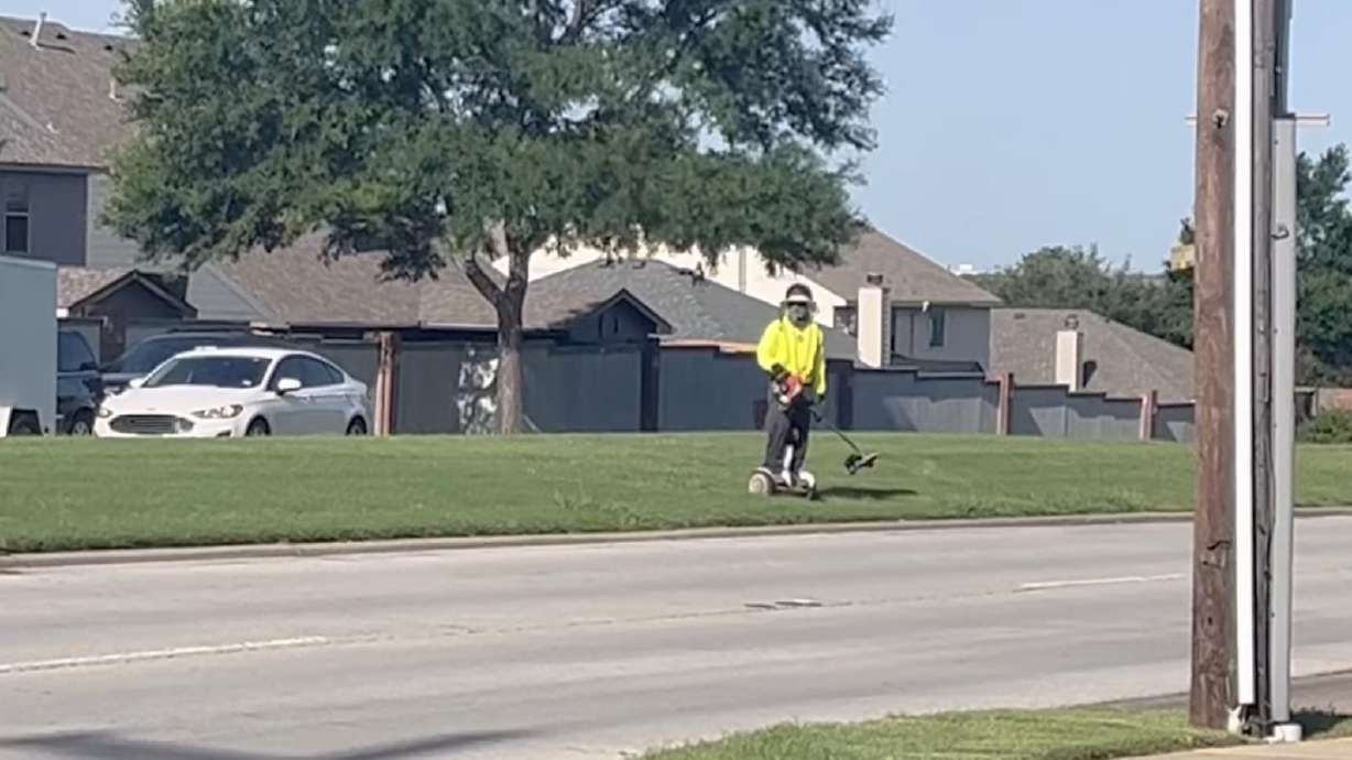 Landscaper is weed eating while riding a Segway.