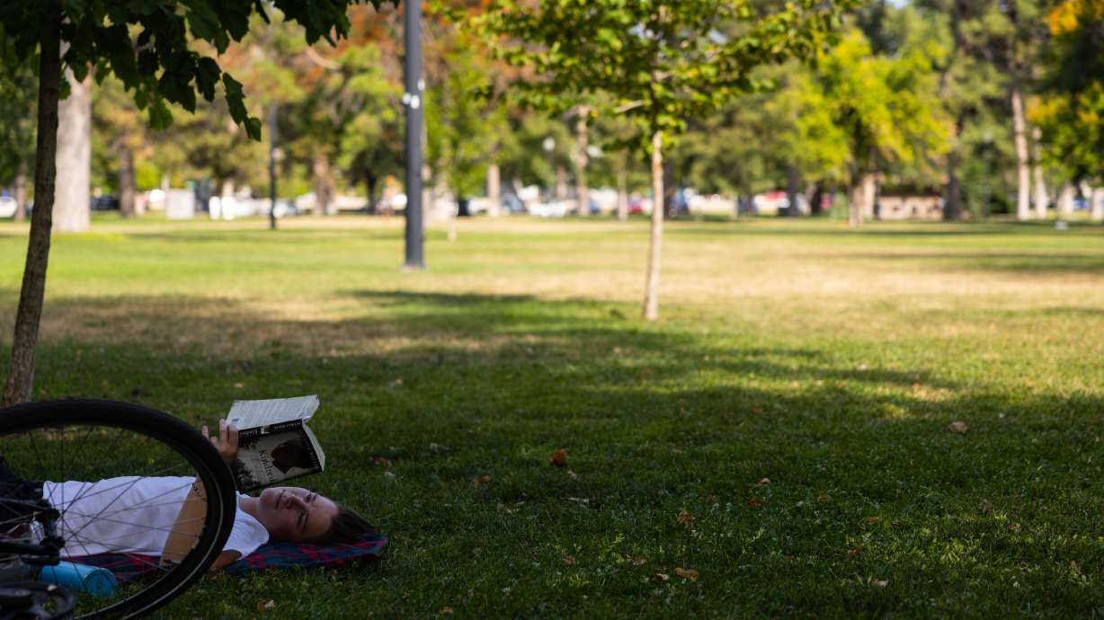 Alexa Dlouhy, 30, reads a book in the shade during a citywide heat advisory at Liberty Park in Salt Lake City on Sunday. The city could set a new record for its highest minimum temperature on Monday.