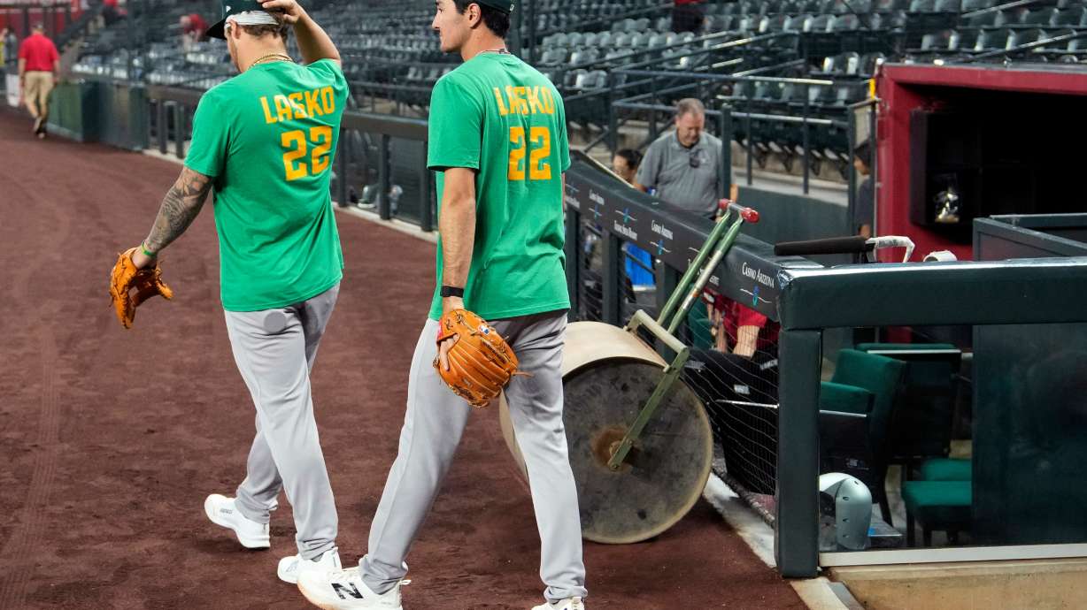 Athletics' Tommy White, left, and Alika Williams wear a Lasko No. 22 t-shirt in honor of injured Athletics minor league player Ryan Lasko prior to a baseball game against the Arizona Diamondbacks, Wednesday, July 22, 2026, in Phoenix.