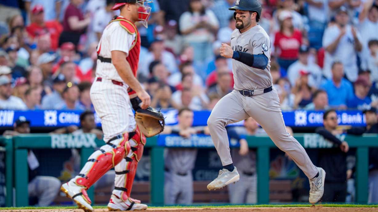 New York Yankees' Austin Wells, right, comes in to score on the single by Cody Bellinger as Philadelphia Phillies catcher J.T. Realmuto, left, looks on during the sixth inning of a baseball game, Saturday, July 25, 2026, in Philadelphia.