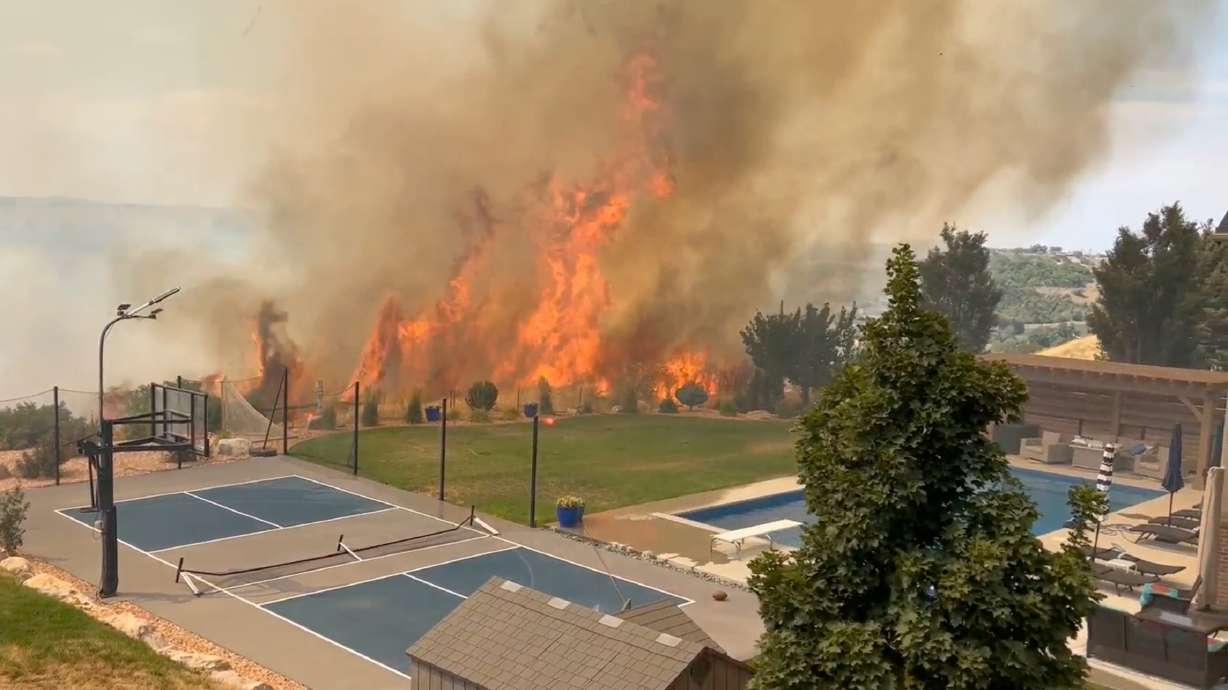 A fire in an undeveloped area south of Washington Terrace on Monday, torched around 45 acres, forced the evacuation of a nearby neighborhood and damaged a home. The photo shows the fire near a Washington Terrace home.