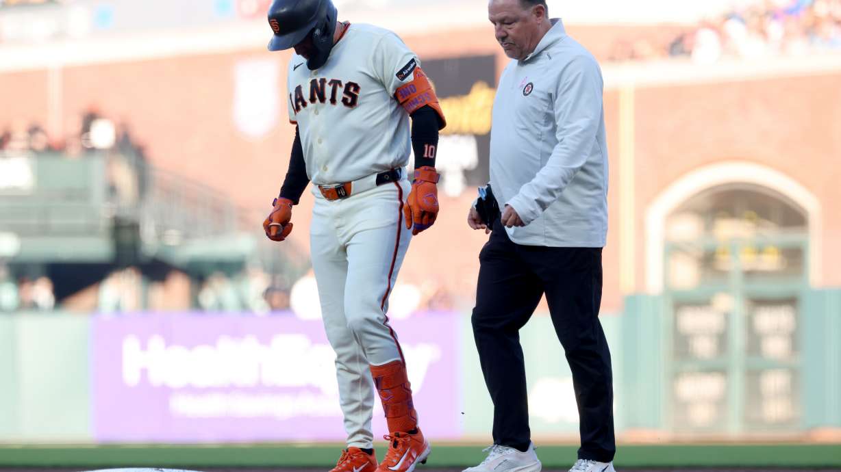 San Francisco Giants' Casey Schmitt, left, walks off the field with an injury accompanied by athletic trainer Dave Groeschner, right, during the second inning of a baseball game against the Milwaukee Brewers in San Francisco, Monday, July 27, 2026.