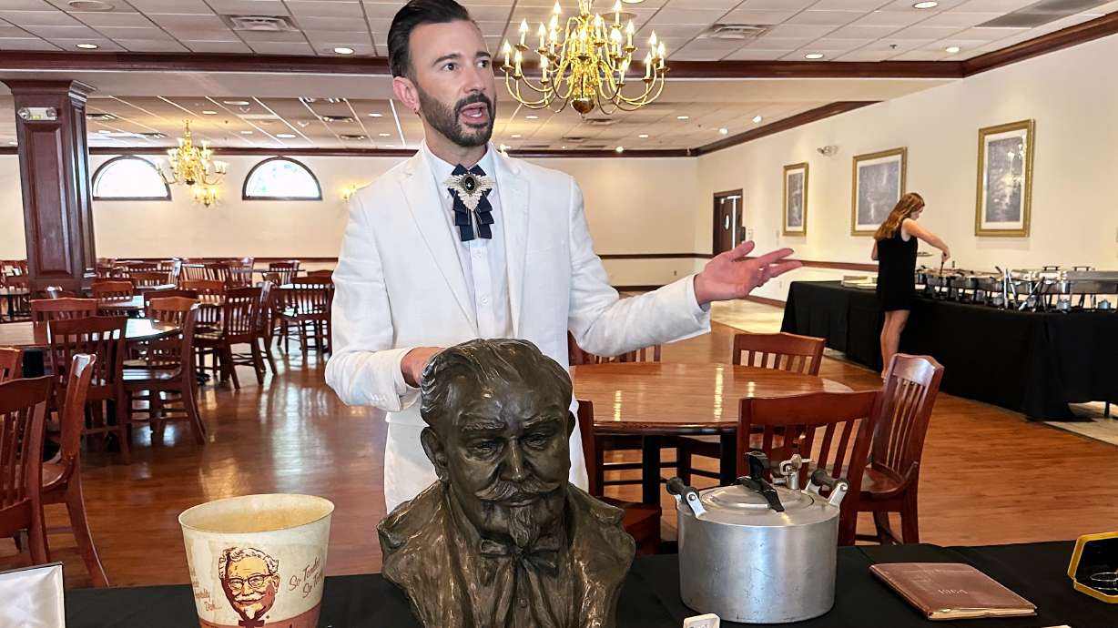 Auctioneer Jonathan Klunk gestures to a display of personal items owned by KFC founder Harland Sanders, Wednesday, in Shelbyville, Ky. Sanders' pressure cooker, black bow tie and dozens of his personal items are up for public auction.