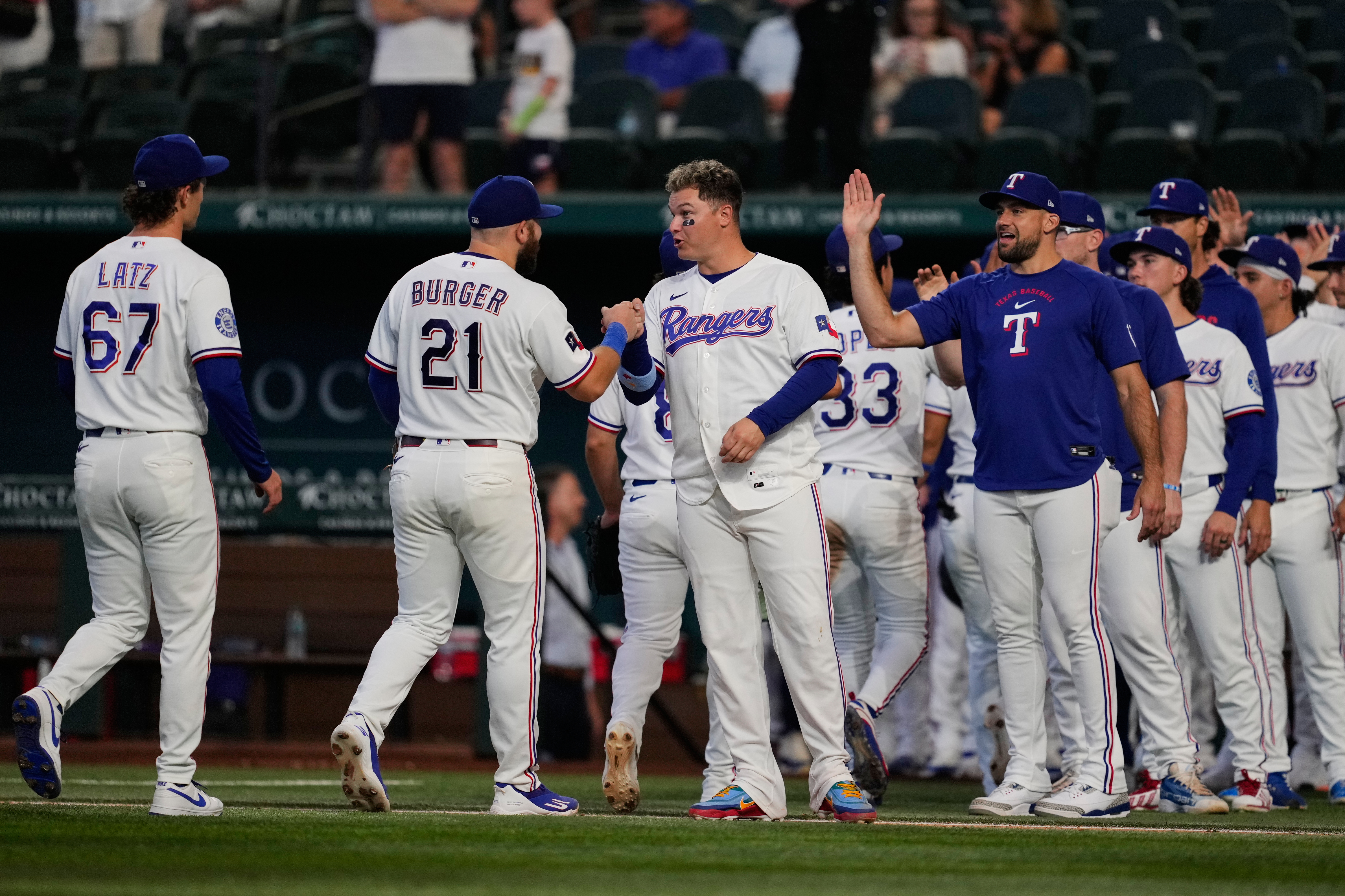 Texas Rangers' Jacob Latz (67), Jake Burger (21), Joc Pederson, center, Nathan Eovaldi, right and the rest of the team celebrate their win against the Seattle Mariners in a baseball game in Arlington, Texas, Monday, July 27, 2026. 