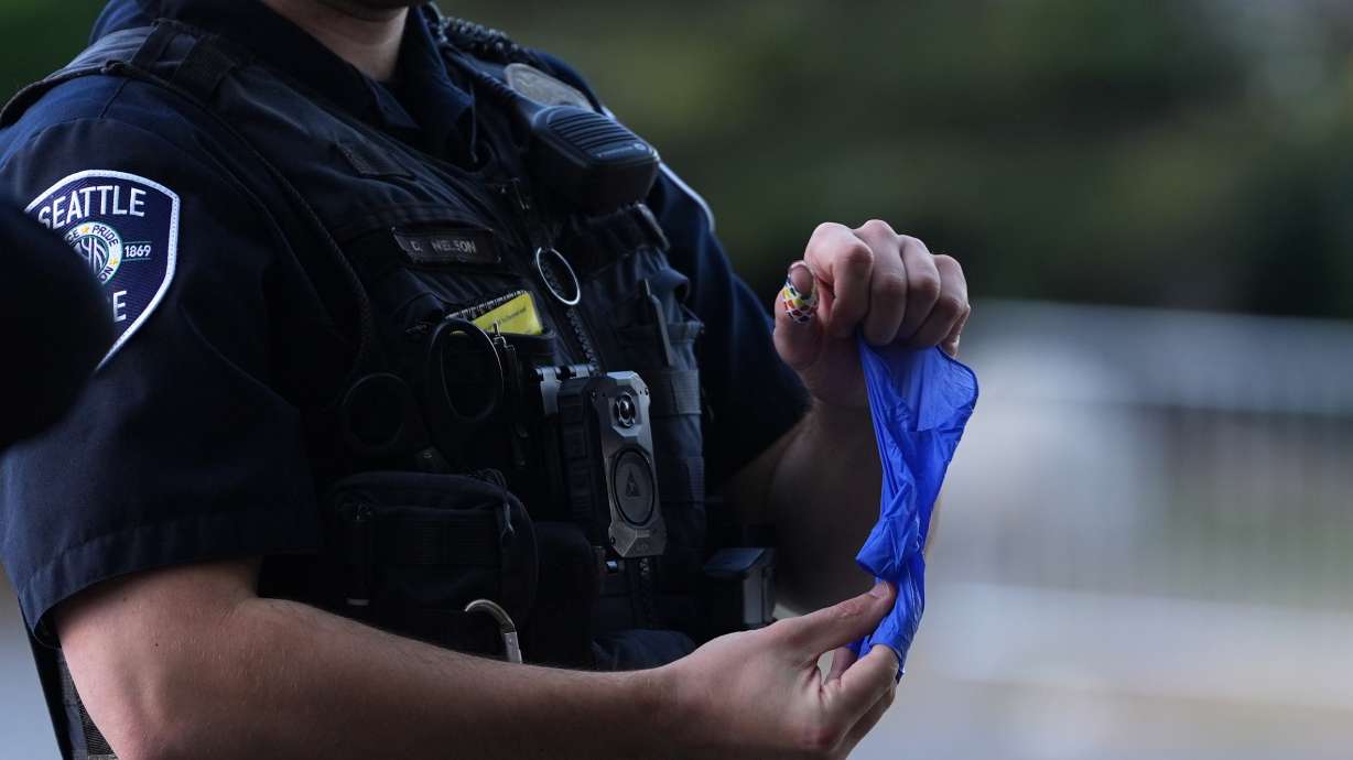 A police officer puts a bullet casing into a rubber glove after he received it from a person who found it, following a shooting at Seattle Center during the Bite of Seattle food festival, Monday. Police said Tuesday the 15-year-old arrested in connection with the festival shooting had a ghost gun.