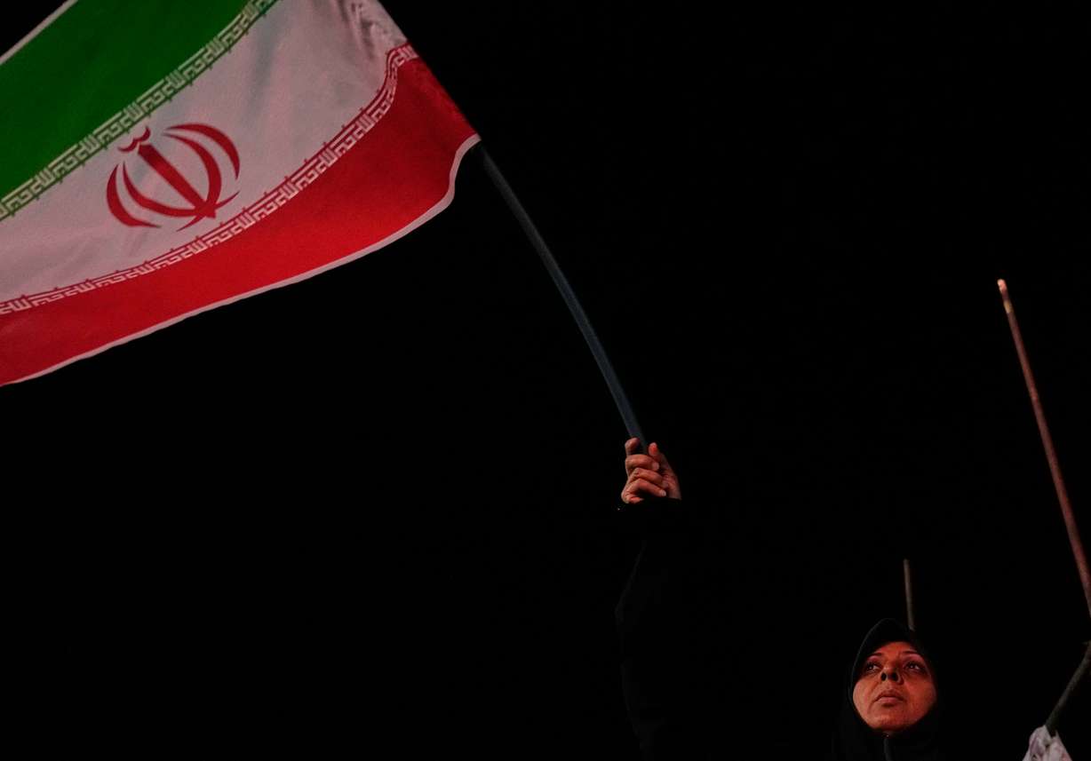 An Iranian pro-government demonstrator waves her country's flag in a gathering at a square in Tehran, Iran, on Tuesday.
