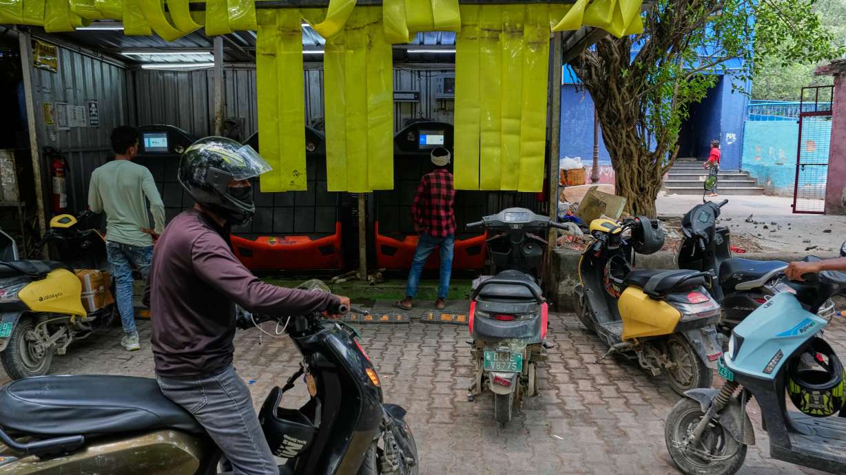 Delivery workers and drivers arrive at a battery-swapping station for electric vehicles in New Delhi, India, July 13. In an affluent neighborhood in Delhi, electric vehicle charging stations near a popular shopping area were busy with drivers powering up their scooters, trucks and cars.
