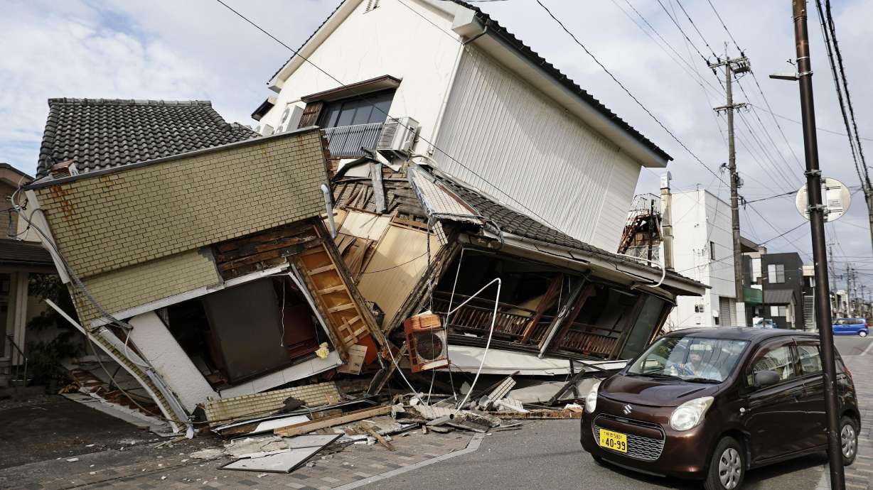 A vehicle passes by collapsed houses after an earthquake in Yatsushiro, Kumamoto prefecture, Japan, Wednesday. A 7.1-magnitude earthquake in the area killed at least 18 people as the search for survivors continued.