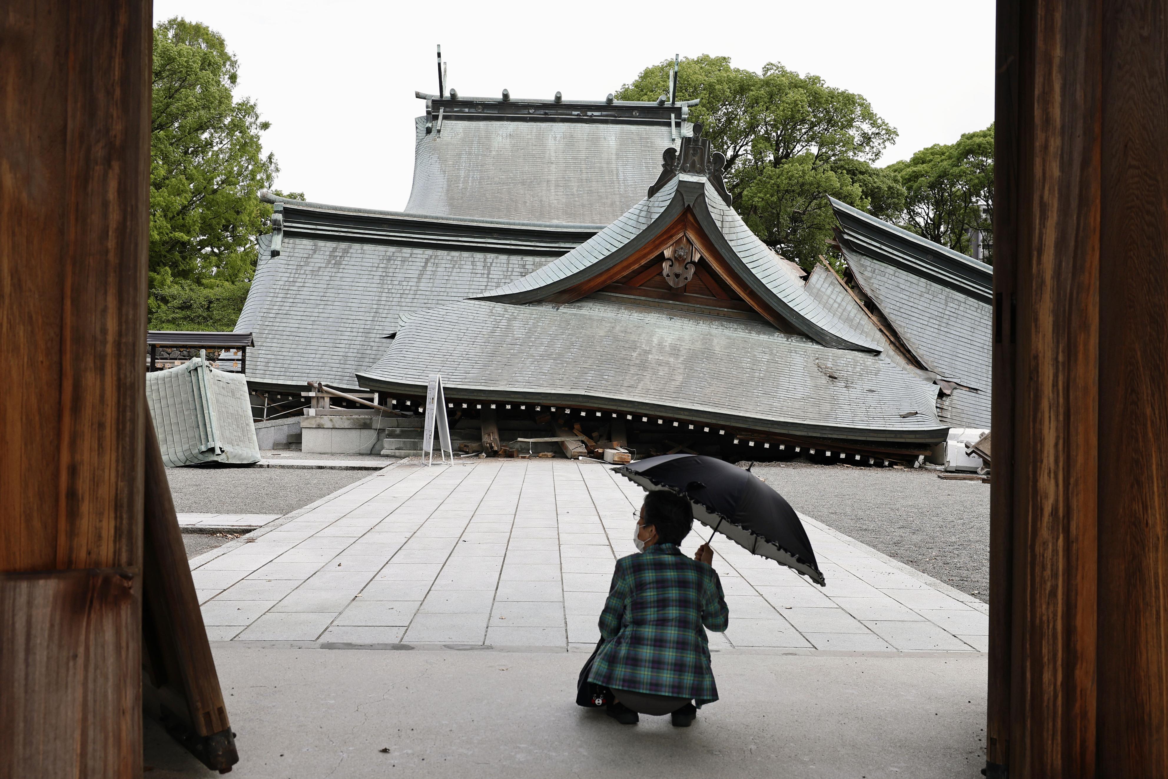 A visitor looks at the fallen roofs of the Yatsuhiro Shrine, a day after an earthquake in Yatsushiro, Kumamoto prefecture, Japan, Wednesday. The 7.1-magnitude quake has killed at least 18 people.