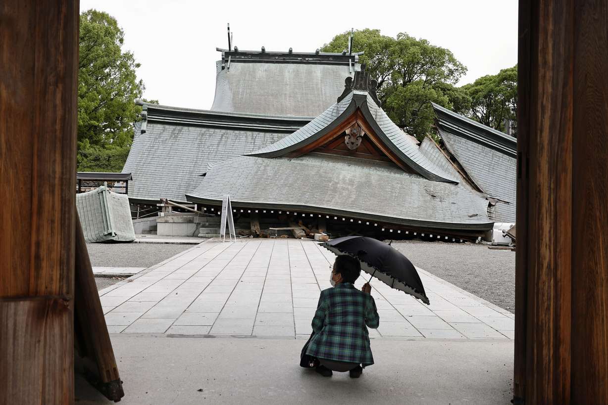 A visitor looks at the fallen roofs of the Yatsuhiro Shrine, a day after an earthquake in Yatsushiro, Kumamoto prefecture, Japan, Wednesday. The 7.1-magnitude quake has killed at least 18 people.