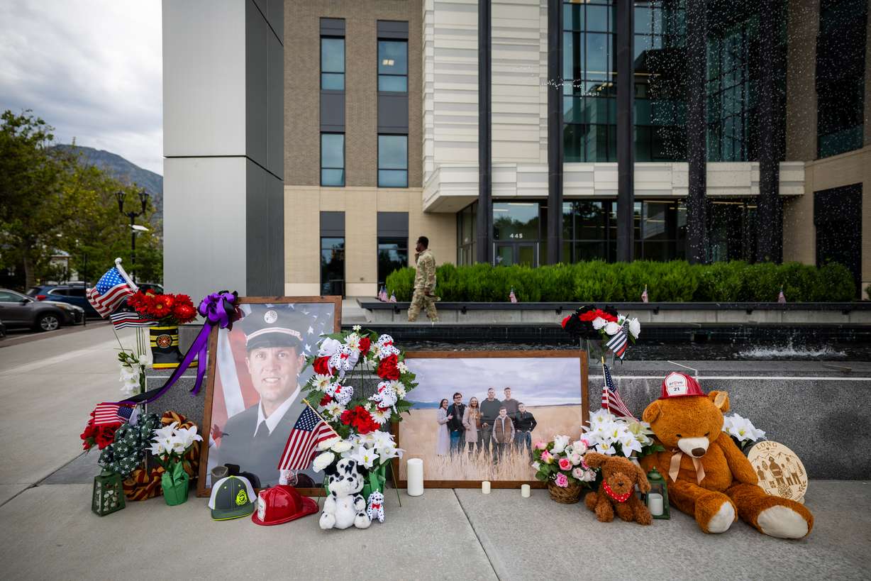 A memorial with flowers, stuffed animals and photos for Provo Fire Capt. Spencer Long and four members of his family who were killed in a flash flood during a weekend camping and hiking trip in Wayne County, outside of City Hall in Provo on July 22.