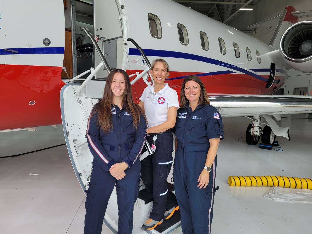 Hailey Meacham (left), Rose Linsler, and Erin Smith pose in front of the medical jet that brought Estelle Santiago home to Utah in January at the Salt Lake City International Airport on Wednesday.