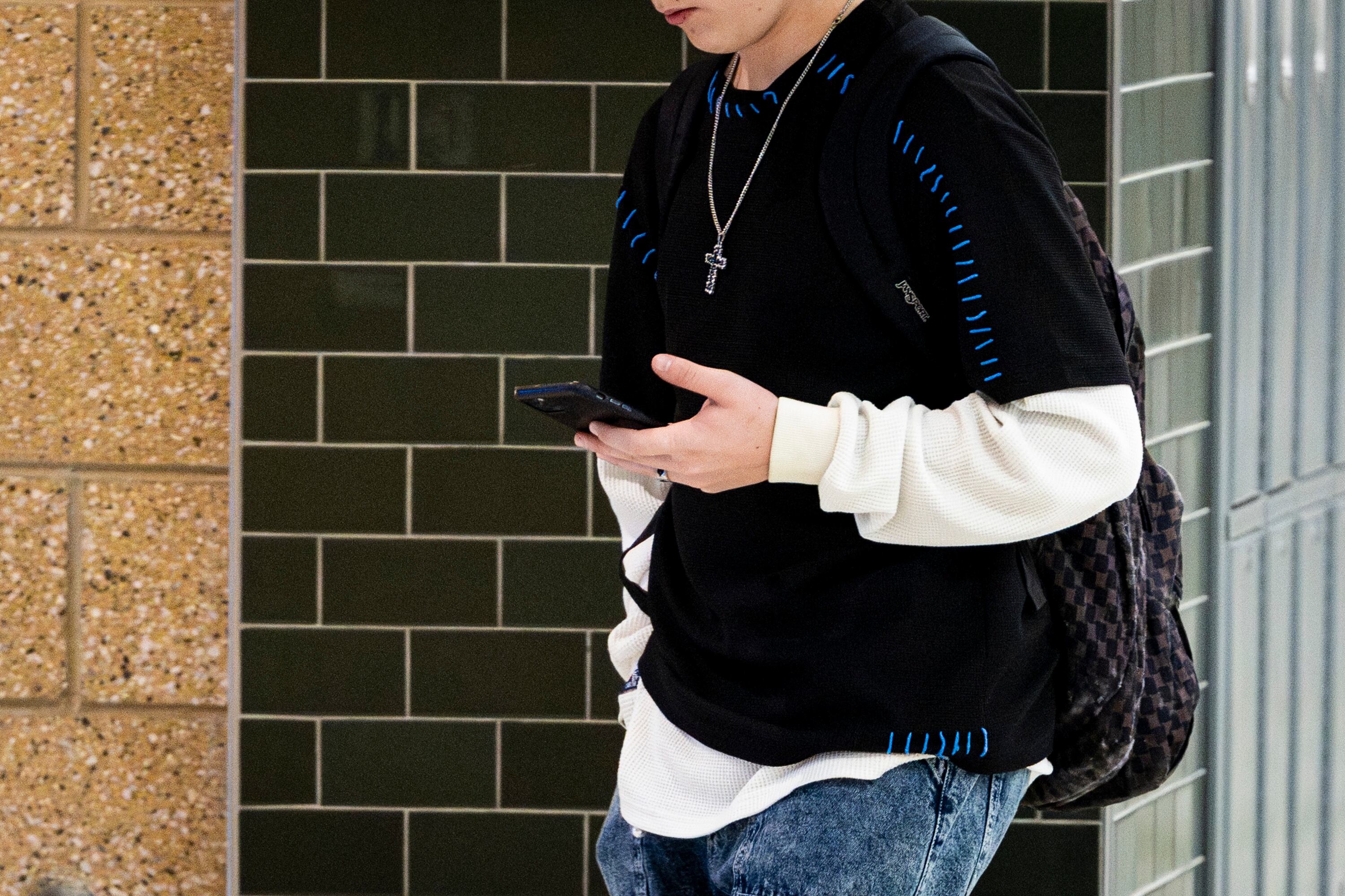 A student uses a cellphone in a hallway at Olympus High School in Holladay on Jan. 8.