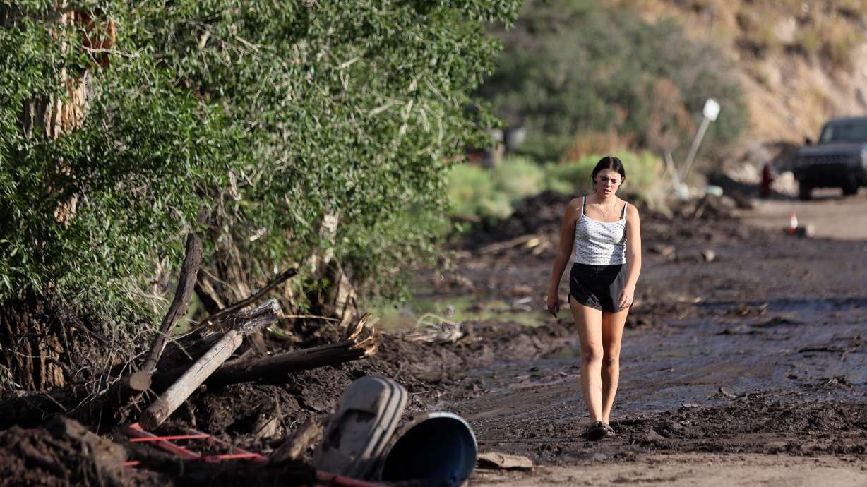 Miley Williams walks on a mud- and debris-covered road after flooding in Beaver on July 20. President Donald Trump signed a major disaster declaration on Thursday that allows for federal assistance in Beaver and Piute counties.