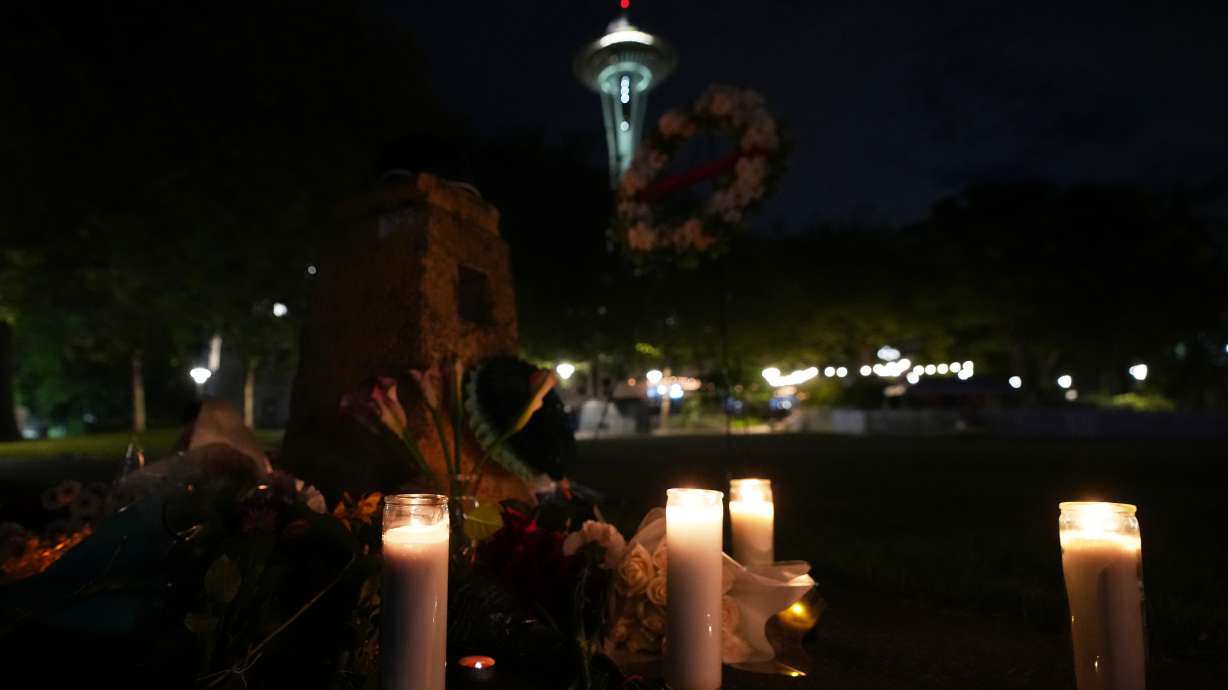 Flowers and candles are seen placed with the Space Needle in the background during the vigil for victims the day after a shooting at Seattle Center during the Bite of Seattle food festival, Monday, in Seattle.
