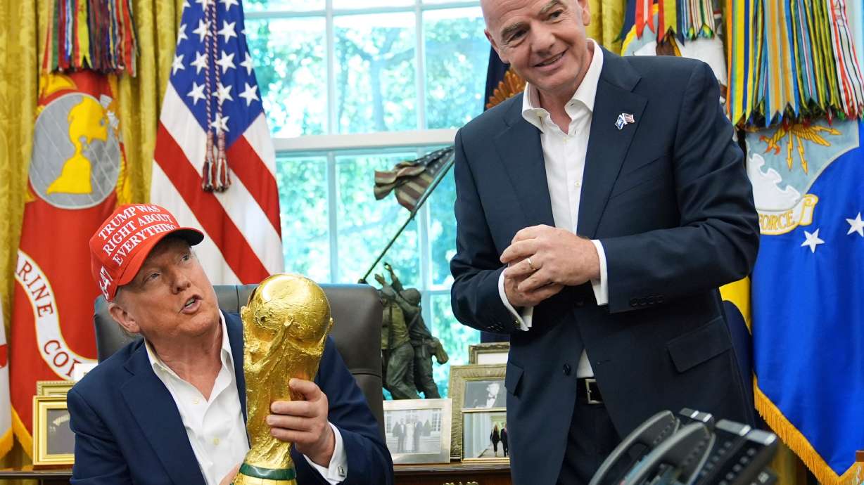 FILE - President Donald Trump holds the FIFA World Cup Winners Trophy as FIFA President Gianni Infantino looks on during an announcement in the Oval Office of the White House, Aug. 22, 2025, in Washington.